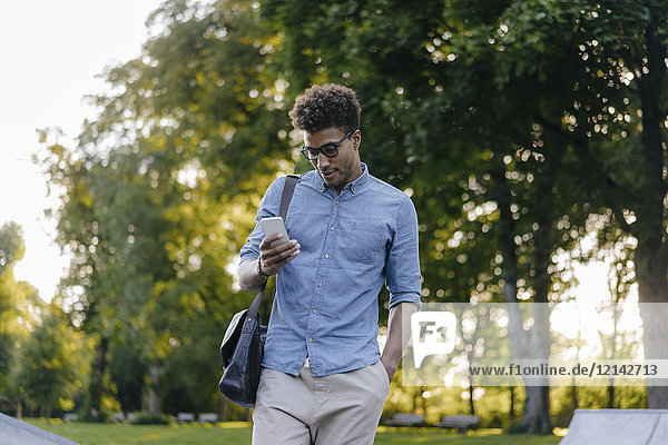 Junger Mann schaut auf Handy im Park