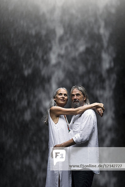 Schönes Seniorenpaar umarmt vor tropischem Wasserfall