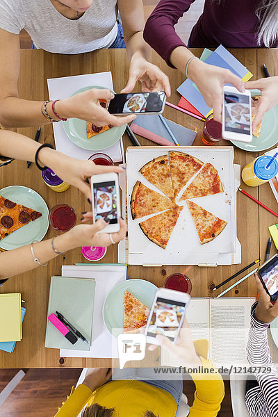 Group of young women at home taking cell phone pictures and sharing a pizza