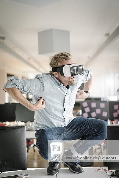 Businessman wearing VR glasses in office pretending to be a monkey