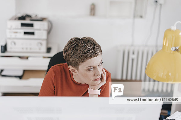 Frau am Schreibtisch im Büro denkend