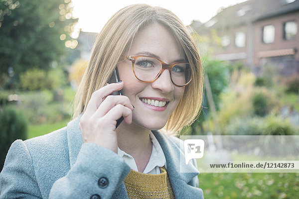 Portrait of smiling woman on cell phone in garden