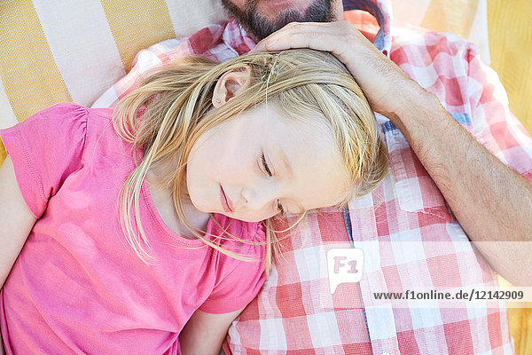 Mädchen entspannt mit ihrem Vater auf einer Decke liegend