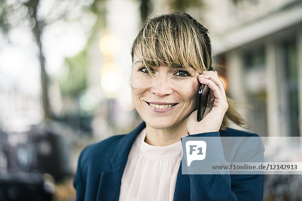 Porträt der lächelnden Geschäftsfrau auf dem Handy im Freien
