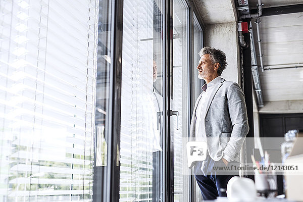 Mature businessman standing in office loooking out of window