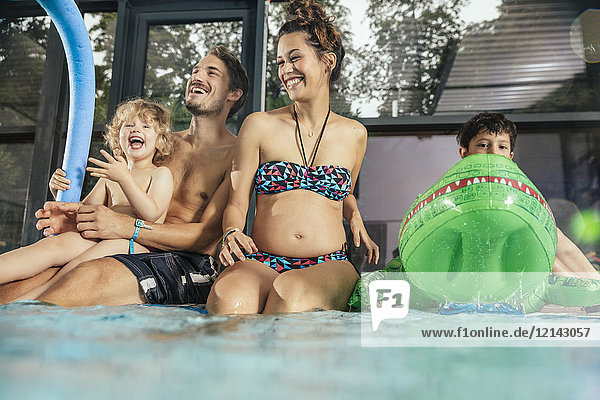 Fröhliche Familie sitzt am Pool im Hallenbad