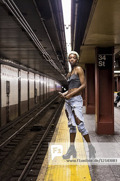 USA  New York City  Porträt einer Frau  die auf dem Bahnsteig der U-Bahn wartet.