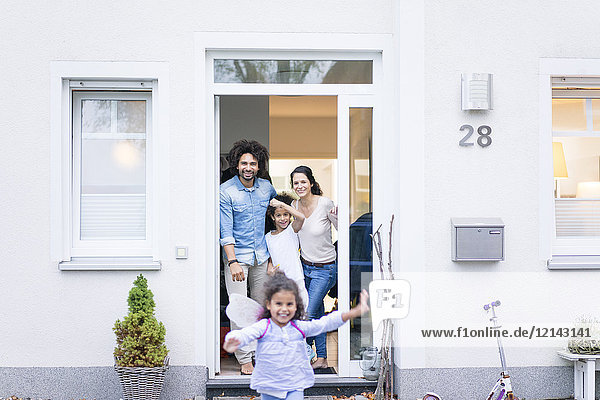 Lachende Familie wartet am Eingang ihres Hauses