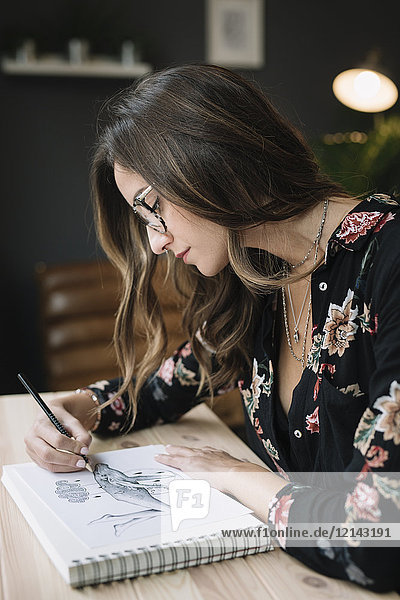 Porträt einer Frau im Skizzenbuch am Schreibtisch im Tattoostudio