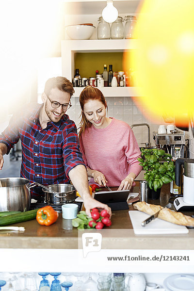 Glückliches junges Paar mit Tablettenkochen in der Küche