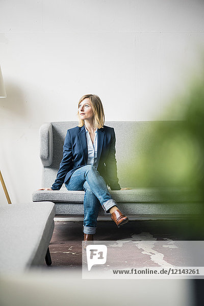Businesswoman sitting on couch in office lounge