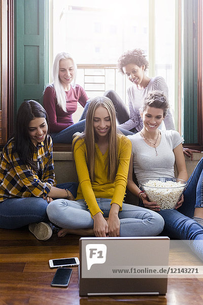 Gruppe von Freundinnen  die gemeinsam zu Hause auf den Laptop schauen