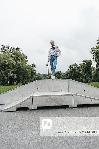 Junge Frau mit VR-Brille im Skatepark mit Skateboard