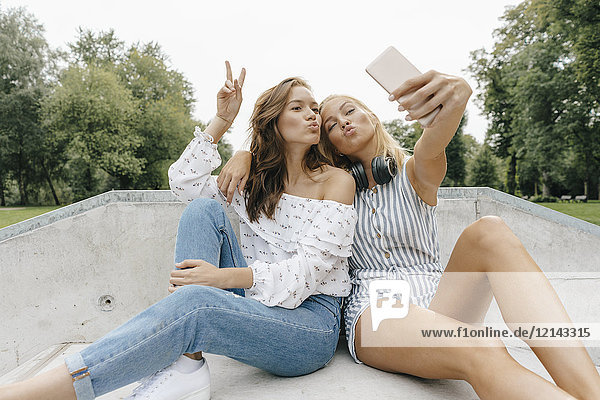 Zwei glückliche junge Frauen  die einen Selfie in einem Skatepark nehmen.