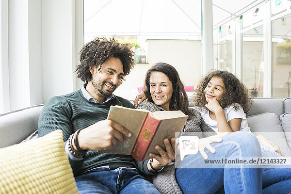 Happy family sitting on couch  reading book