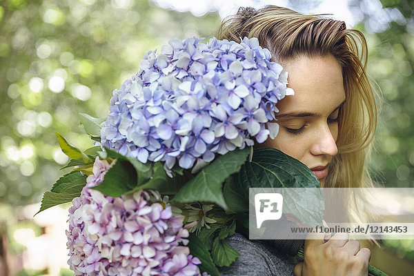 Young woman with closed eyes holding a bouquet of hydrangeas