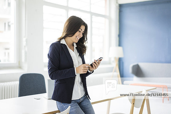 Smiling businesswoman using cell phone in the office