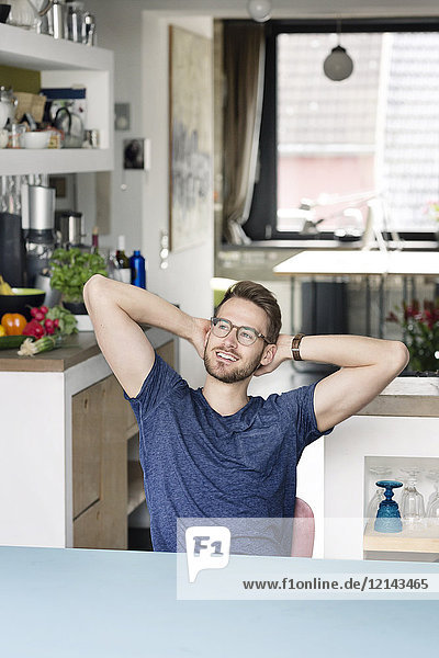 Porträt eines lächelnden jungen Mannes  der zu Hause am Küchentisch sitzt.