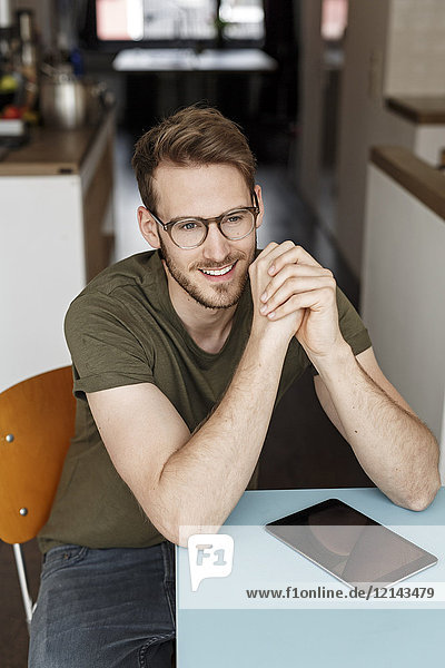 Porträt eines lächelnden Mannes mit Tablette in der Küche zu Hause