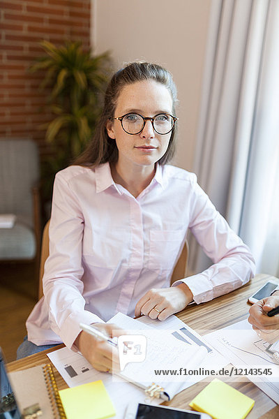 Porträt einer Geschäftsfrau beim Notieren auf dem Tisch im Büro