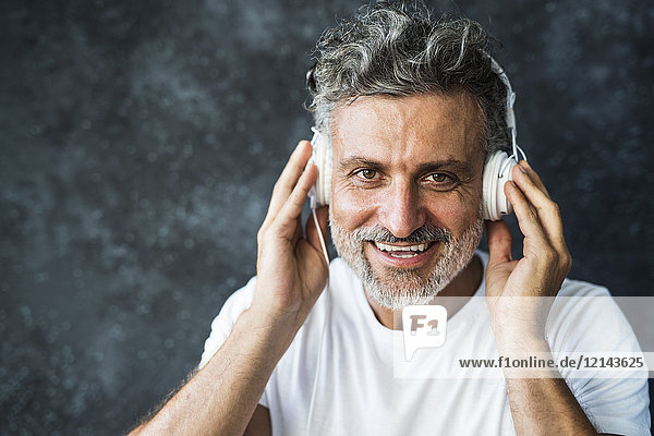 Älterer Mann lächelt  trägt Kopfhörer.