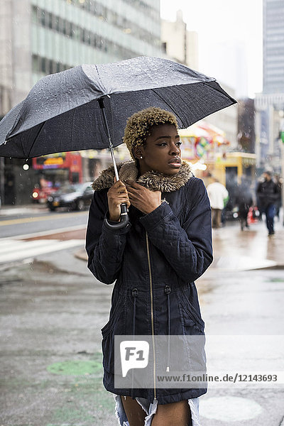 USA  New York City  portrait of young woman with umbrella on rainy day
