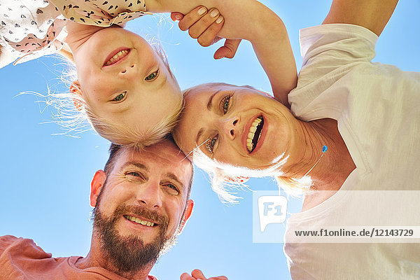 Portrait of happy family huddling under blue sky