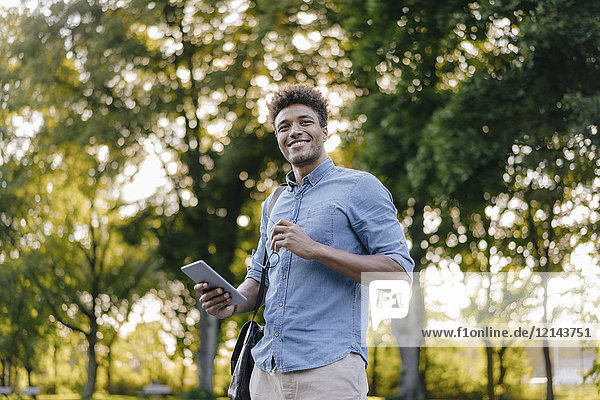 Smiling young man holding cell phone in park