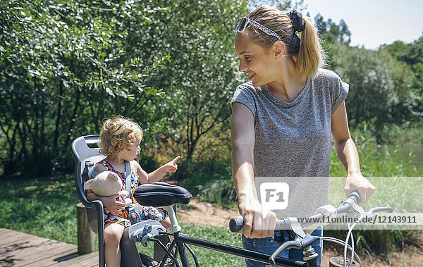 Mutter bei einer Radtour durch die Landschaft mit ihrer Tochter im Kindersitz