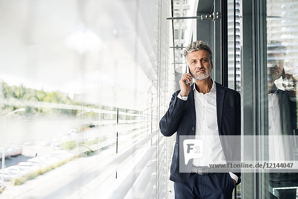 Mature businessman on cell phone at outside sunblind