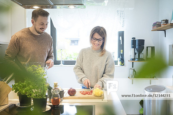 Happy couple preparing salad in kitchen together