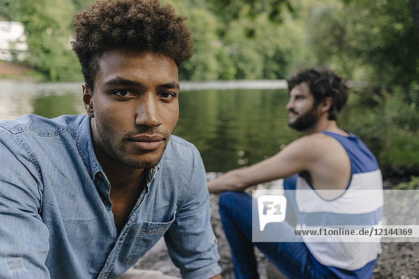 Portrait of young man with friend relaxing at the water