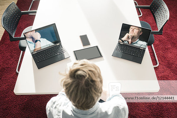 Geschäftsmann mit zwei Laptops  die Bilder von sich selbst zeigen.
