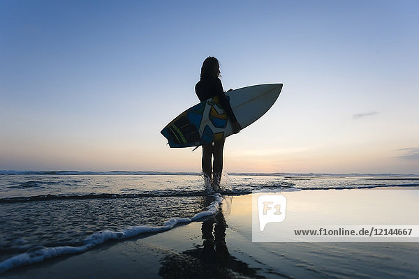 Indonesien,  Bali,  Junge Frau mit Surfbrett