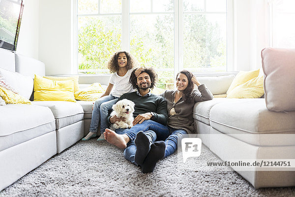 Happy family with dog sitting together in cozy living room