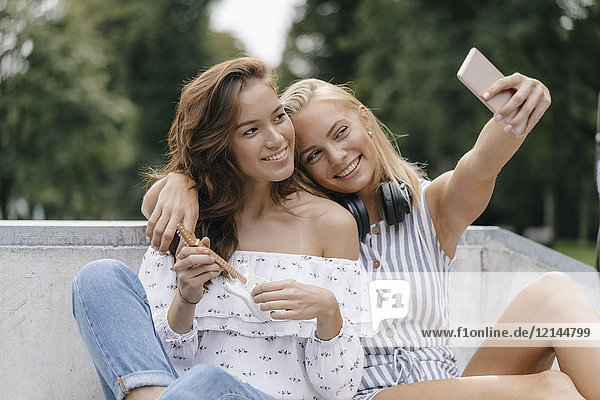Two happy young women taking a selfie in a skatepark