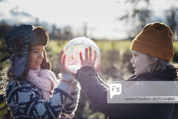Brother and sister looking into crystal ball filled with snow  making a wish
