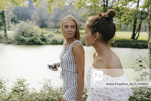 Zwei junge Frauen mit Handy an der Uferpromenade