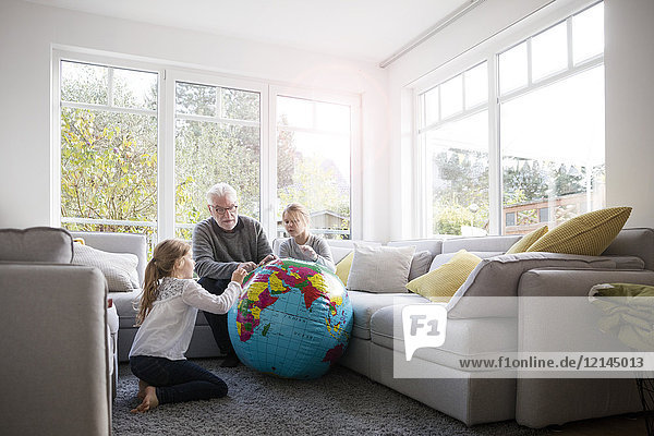 Two girls and grandfather with globe in living room