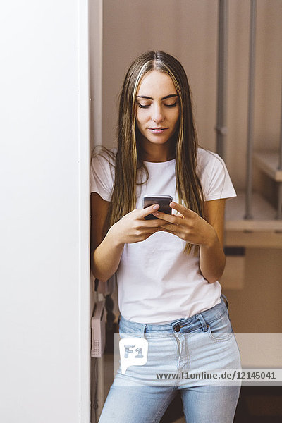 Junge Frau zu Hause mit dem Handy