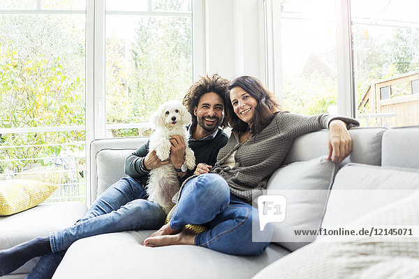Happy family with dog sitting together in cozy living room