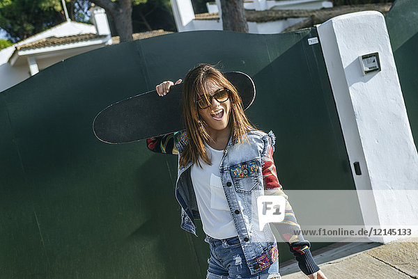 Porträt einer jungen Frau mit Skateboard auf den Schultern