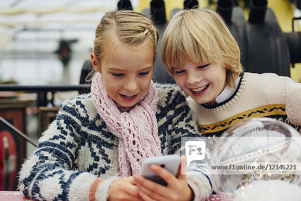 Bruder und Schwester senden SMS mit Weihnachtswünschen auf dem Smartphone