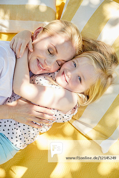 Fröhliches Mädchen umarmt Mutter auf einer Decke