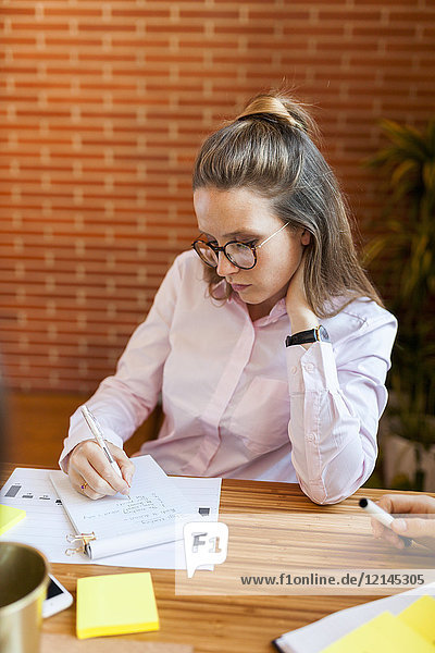Businesswoman taking notes on table in office