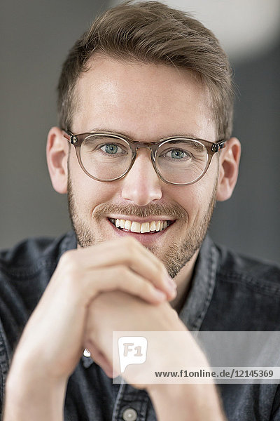 Porträt eines lächelnden jungen Mannes mit Brille