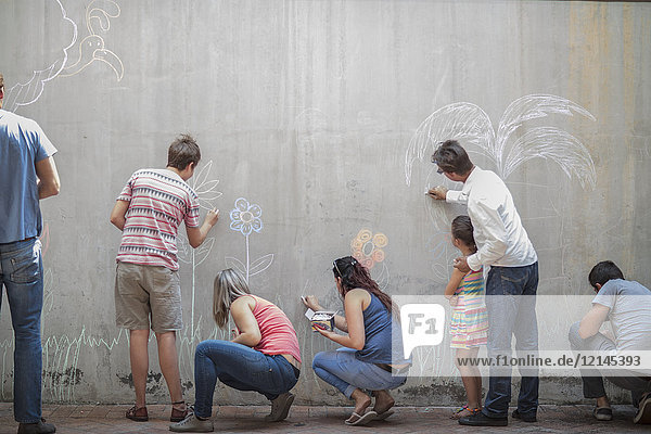 Menschen  die bunte Bilder mit Kreide auf einer Betonwand zeichnen