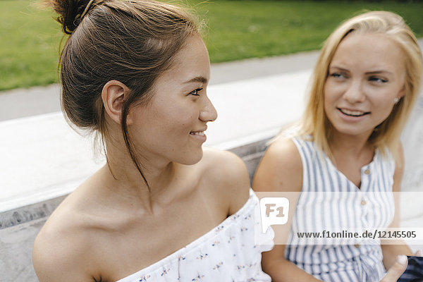Zwei lächelnde junge Frauen sprechen im Freien