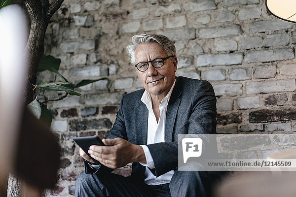 Geschäftsmann sitzend im Café  mit Smartphone