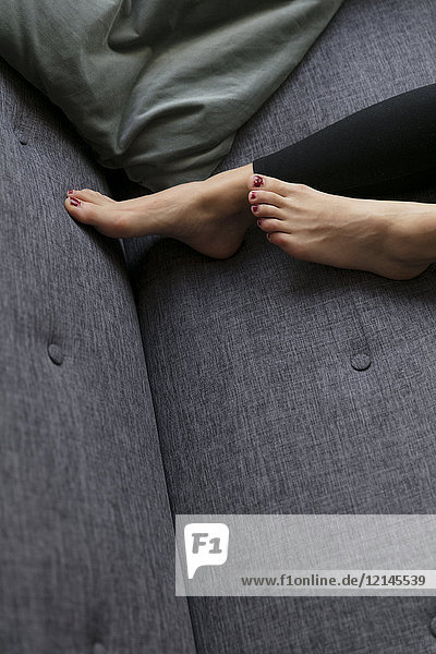 Feet of woman lying on couch at home
